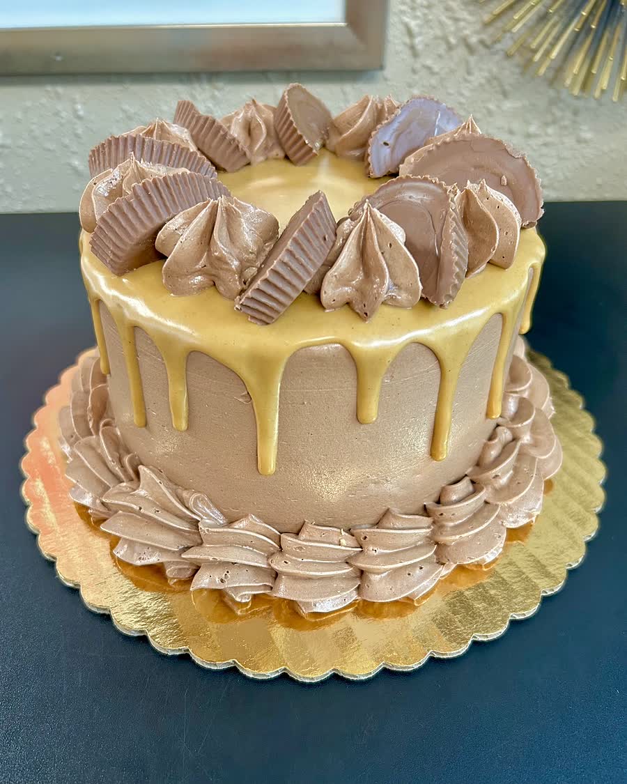 A gluten-free chocolate peanut butter cup cake with a peanut butter drip and peanut butter cups around the top